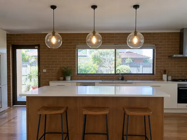 Three glass pendant lights over a kitchen island in a brick-walled home interior in Matraville